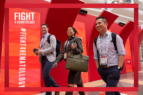 Smiling annual meeting attendees walk in front of a Fight4hematology sign.