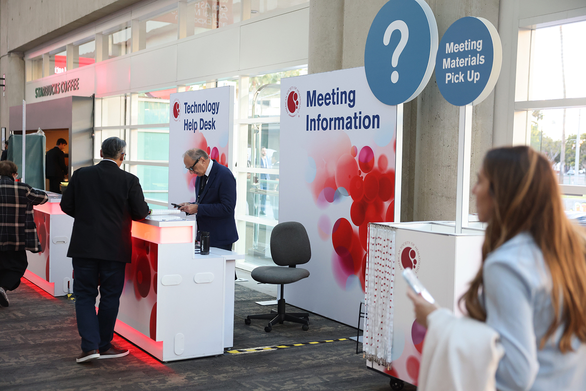 A group of people at the ASH annual meeting makes inquiries at the information desk.