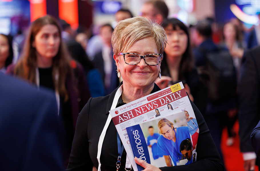 A woman smiling and holding ASH News Daily during the Annual Meeting