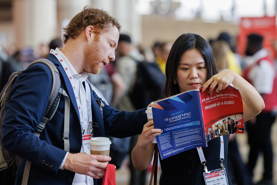 A photo of a man and a woman looking at the Program at a glance booklet for the next session during the Annual Meeting